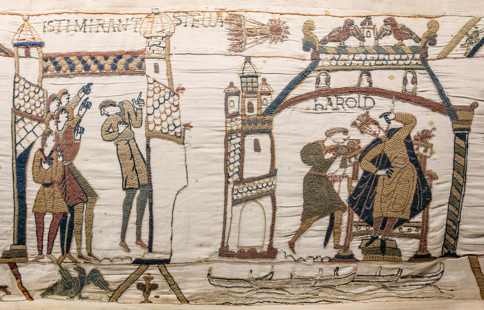 A scene from the Bayeux Tapestry: embroidered men point up at a comet with a flaming tail, beside Harold seated on a throne